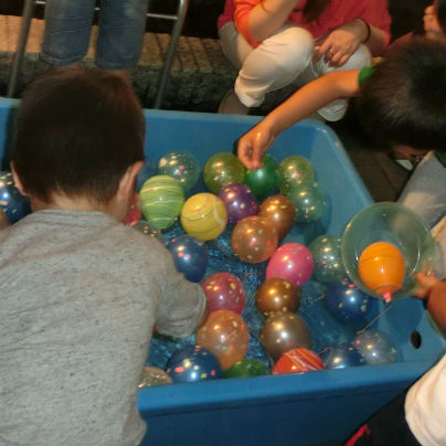 水色のＦＲＰ製水槽の中にたくさんのボールが入っていて、数人の子供らが懸命に取ろうとしています