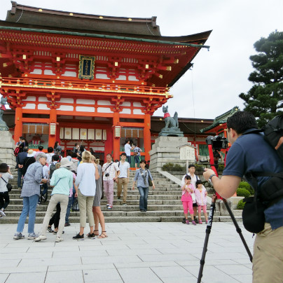 伏見稲荷大社で記念撮影をする男性の観光客。三脚にカメラを固定して撮影しています。