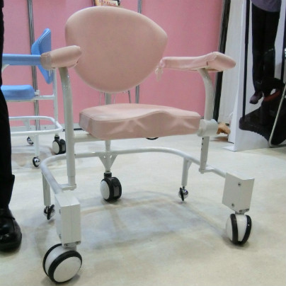 白い床にピンクの背もたれと肘掛けをもつ椅子が置いてあります
