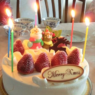 テーブルの上には白いクリスマスケーキ、苺が前に４つ、その奥に２つ、苺のあいだでサンタクロースと熊の人形が乗っています。
