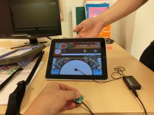 iPadに貼り付けたiPad Touchのボタンを押してでナムコ太鼓ゲームで遊んでいます。