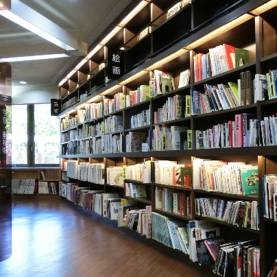 箕面中央図書館で左奥に大きな窓、右側に木製の棚とたくさんの書物