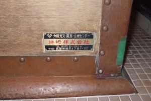 木風呂にとりつけている神崎(株)の銘板。木風呂の側板、右斜め下の角近くに横長の真鍮製銘板を貼り付けている。