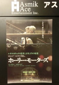 映画、ホーリー・モーターズのポスターが黒い壁に貼ってあります。主演のドニ・ラヴァンが、カイリー・ミノーグを抱えて階段を上がるシーンです。