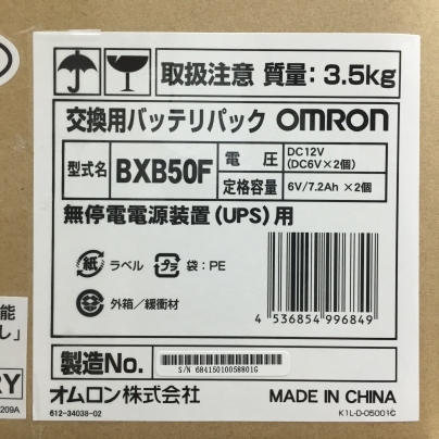 段ボール箱に白地に黒い文字で交換用バッテリパック OMRON BSB50F と、書いてあります。