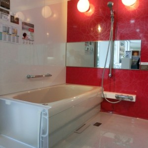 システムバスは白い床と壁に白い浴槽。鏡のある壁だけは真っ赤な壁になっています。