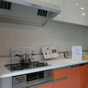 システムキッチンはオレンジの扉、レンジフードがお掃除しやすいタイプです