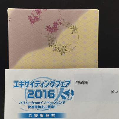 和菓子の包み紙は黄土色と薄紫。その手前にエキサイティングフェア２０１６と書いた招待状が置いてあります。