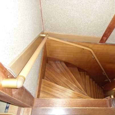 階段の上階ら下に向かって撮影しています。急な階段の左壁にフリーアール手すりが通っています。