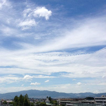 雲の切れ間に青空がのぞく下側に六甲山が写っています。