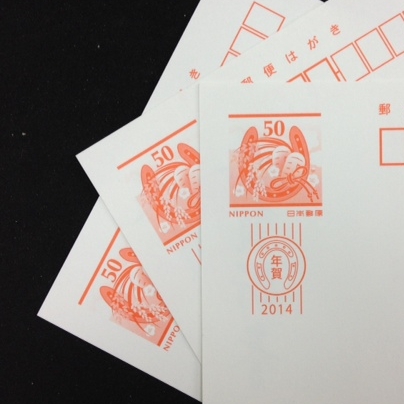 日本郵便の年賀状を３枚重ねて扇状に開き、切手の部分をアップで写しています。