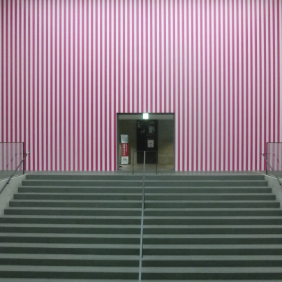 階段を上がると、壁一面が薄紫色と白の縦縞、その中央に入り口が開いています。