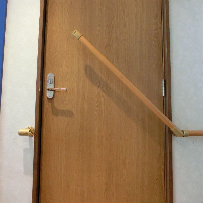 扉を横切る遮断機手すりが斜めに上がっている様子。