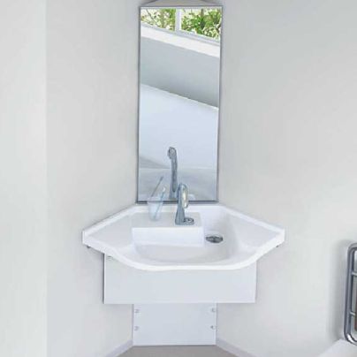 白い壁のお部屋のカドに白い手洗い器、その上に細長い鏡が設置してあります